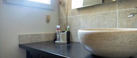 A bathroom with a large ceramic sink, a towel rack, and a mirror above the sink.
