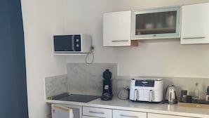 Una cocina compacta equipada con microondas, cafetera, tostadora y un refrigerador pequeño.