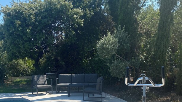 Una piscina con jacuzzi, mobiliario exterior y una cámara de seguridad.