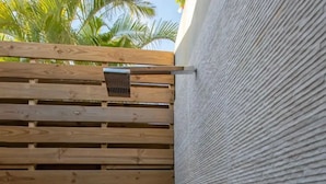 Une porte en bois, dotée d’une poignée en métal et d’une grille d’aération, qui donne sur une terrasse carrelée.