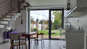 A modern kitchen with a dining area, a staircase, and a view of the backyard.