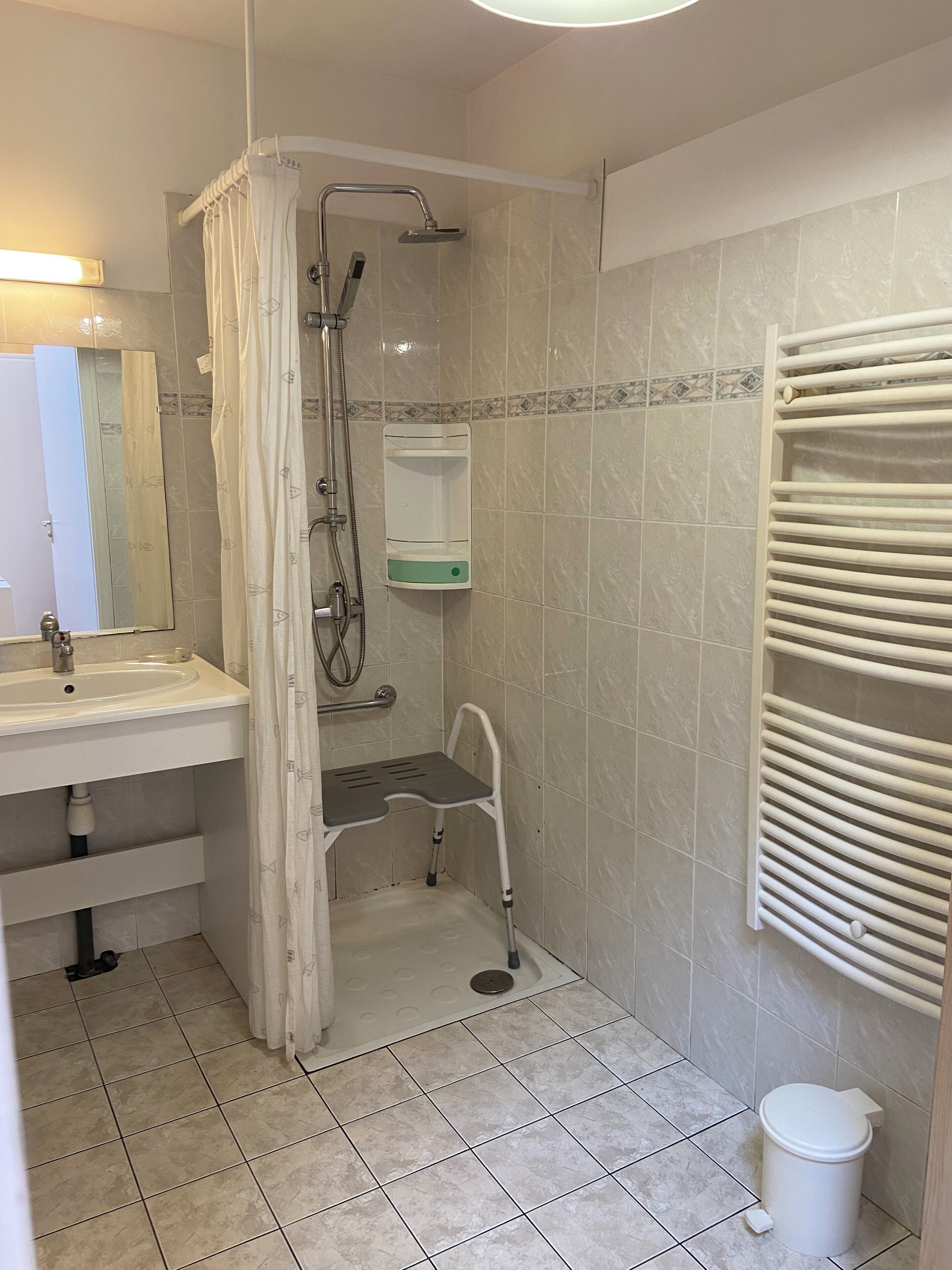 A bathroom with a shower, a sink, a toilet, and a towel rack.
