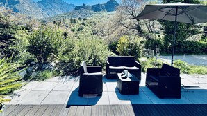 Une terrasse avec des meubles d’extérieur, un grand parasol et une vue sur les montagnes.