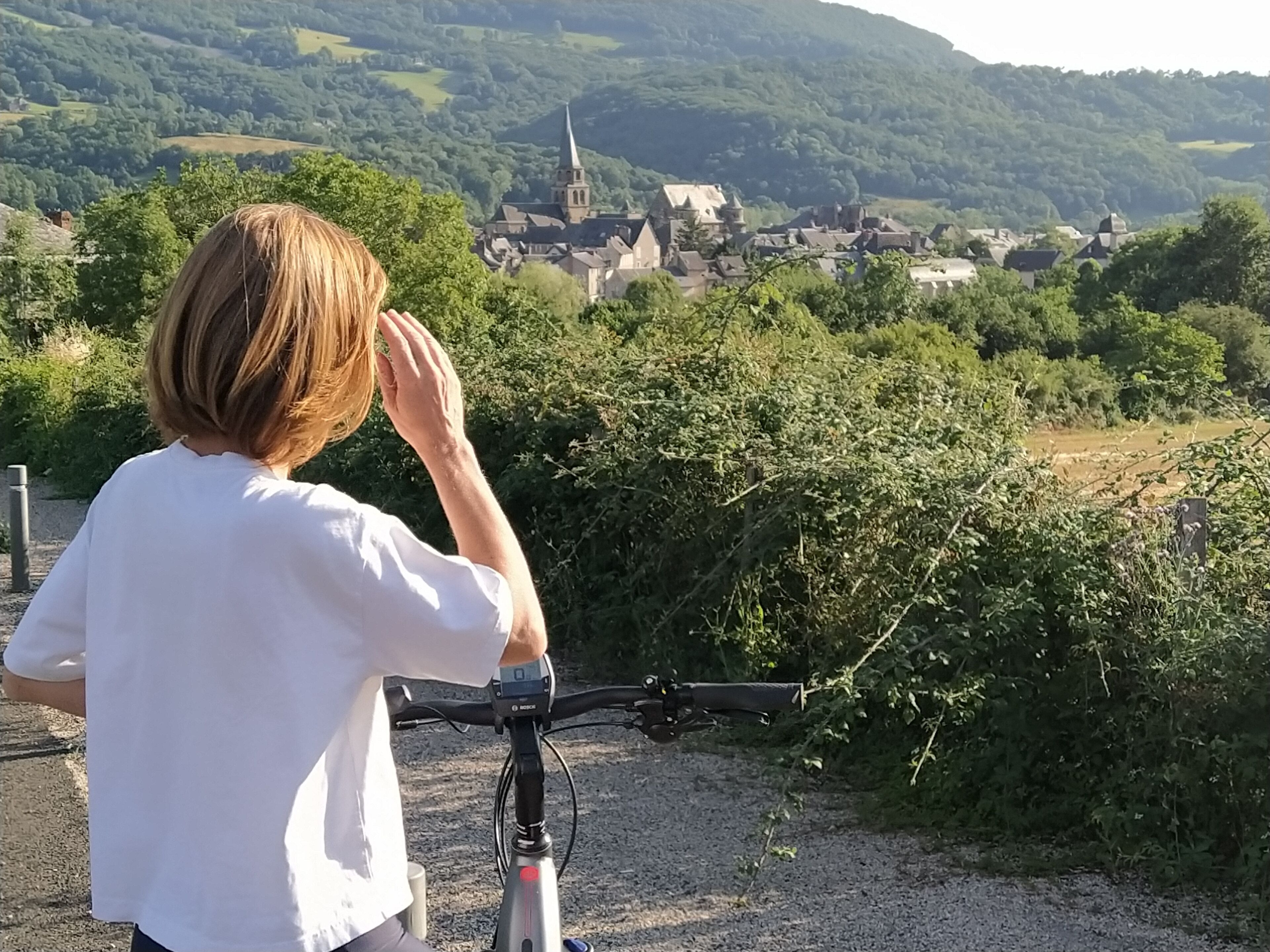 Una persona en bicicleta con vistas a un pueblo y una iglesia al fondo.