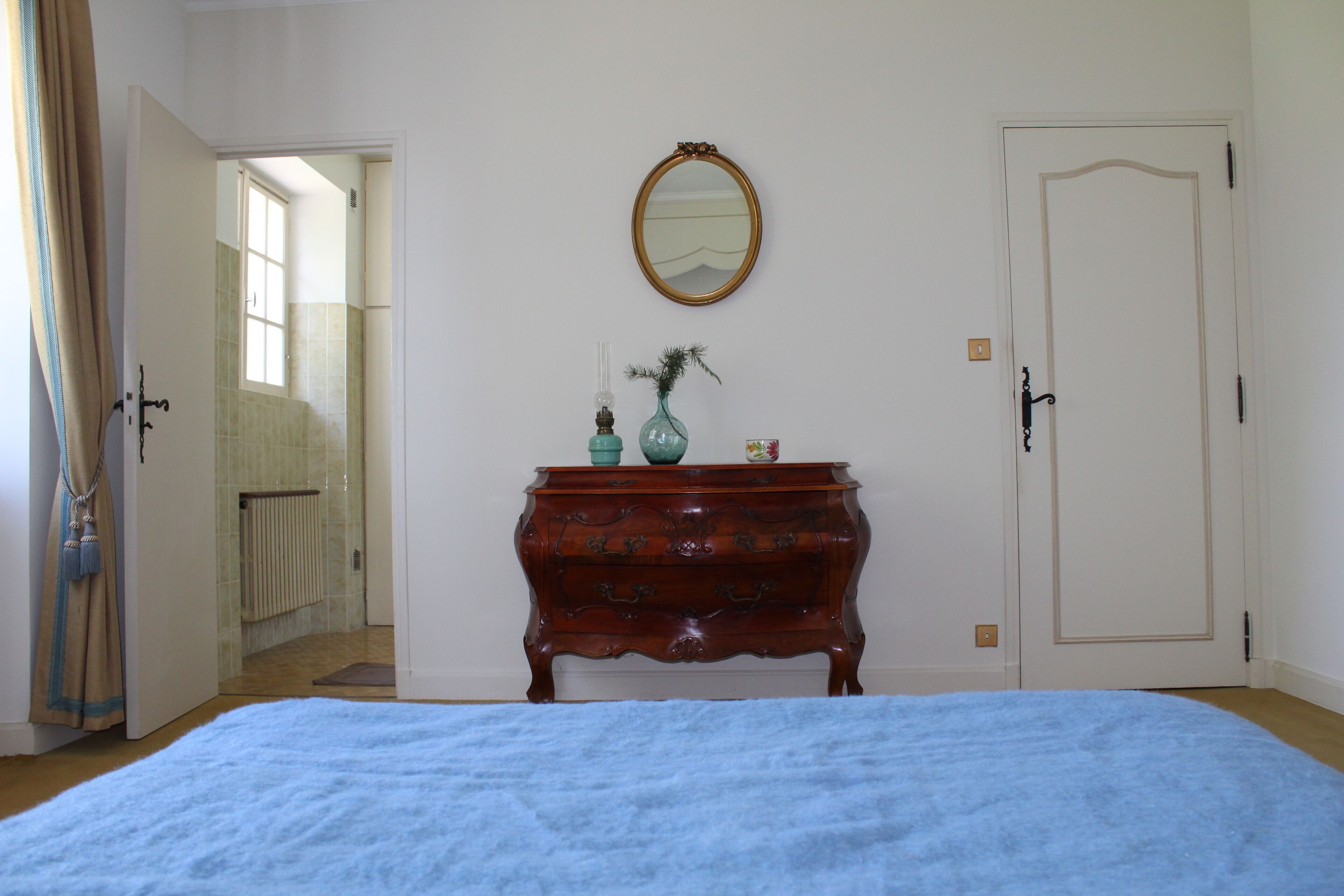 Een slaapkamer met een bed, een kaptafel, een spiegel en een deur.