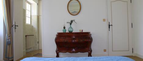 Een slaapkamer met een bed, een kaptafel, een spiegel en een deur.