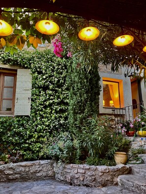 Un mur de pierre avec une porte en bois, une fenêtre avec une lampe et un escalier menant à une autre porte.