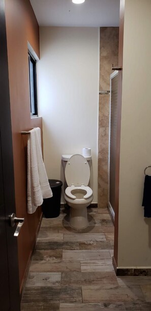 A bathroom with a toilet, a towel rack, and a shower area. - Casa Los Sauces (Rio Verde)