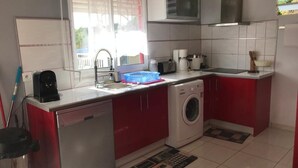 A compact kitchen with a washing machine, a coffee maker, and a microwave.
