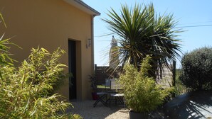 A building with a gravel patio, a table and chairs, and a potted plant. - COTTAGE IDEALLY LOCATED (Saint-Évarzec)
