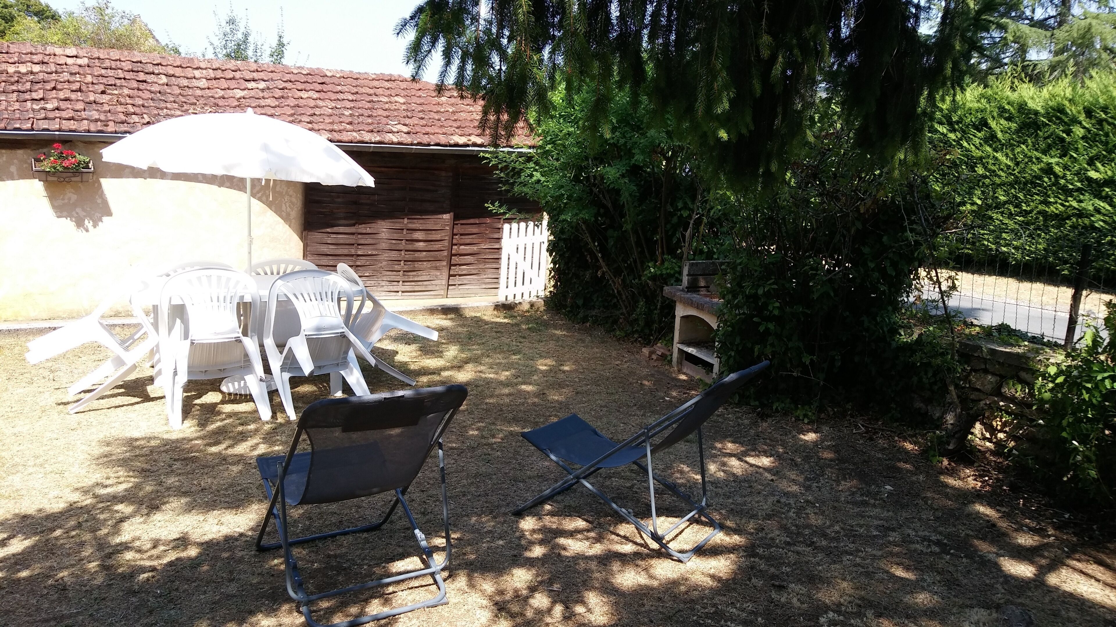 A patio area with a table and chairs, a folding chair, and an umbrella.