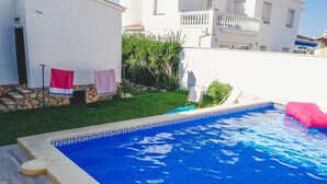 En swimmingpool med en kant av kakel, en stenmur och en gräsyta med en flagga.
