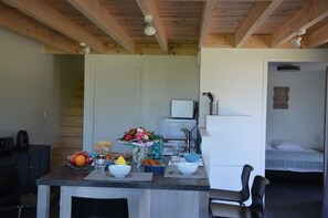 Eine kompakte Küche mit Essbereich, einem Kühlschrank, einer Spüle und einem kleinen Tisch mit Blumen in einer Vase.
