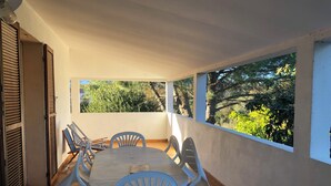 A covered patio with a round table and chairs, large windows, and a view of greenery. - Mare è Monte 4,5 km from the sea. Ideal for touring Corsica (Ghisonaccia)