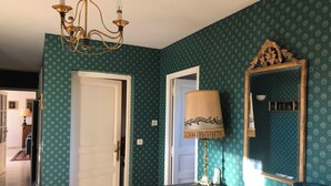 A room with teal patterned wallpaper, a chandelier, a mirror with a decorative frame, and a table with a lamp. - Mare è Monte 4,5 km from the sea. Ideal for touring Corsica (Ghisonaccia)