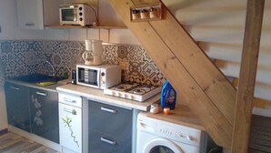 Une cuisine compacte équipée d’un four à micro-ondes, d’une machine à café et d’un lave-linge.