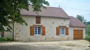 A stone building with a gravel driveway and wooden shutters on the windows.