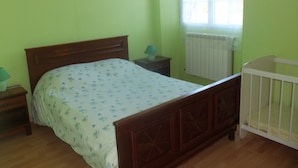 A bedroom with a wooden bed, a nightstand, a lamp, and a crib.