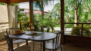A wooden deck with a round table and four chairs, a hat on the table, and two drinks. - Farniente in Martinique (Le Vauclin)