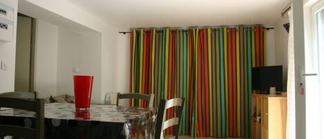 A dining area with a table, chairs, and a red cup. There is a colorful striped curtain in the background.