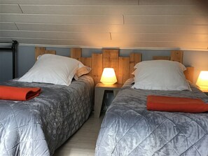 A double room with two beds, each with a wooden headboard and white pillows. There are two bedside lamps providing light. - Luxury cottage  (SAINT EVARZEC)