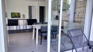 Ein modernes Interieur mit Essbereich, Fernseher und durch Glastüren einsehbarer Küche.