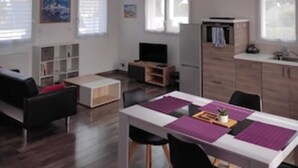 Una sala moderna con un sofá, un televisor y un comedor con una mesa y sillas.