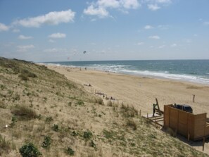 Une plage avec une structure en bois, des dunes de sable et l’océan.