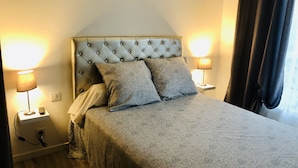 A neatly made bed with a tufted headboard, two bedside lamps, and a bedside telephone.