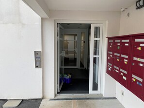 A hotel entrance with a glass door, a mail slot, and a red mailbox. - BaskoParadis I Apt Design I Adapted reduced mobility I Bed 160 I Terrace I Patio (Cambo-les-Bains)