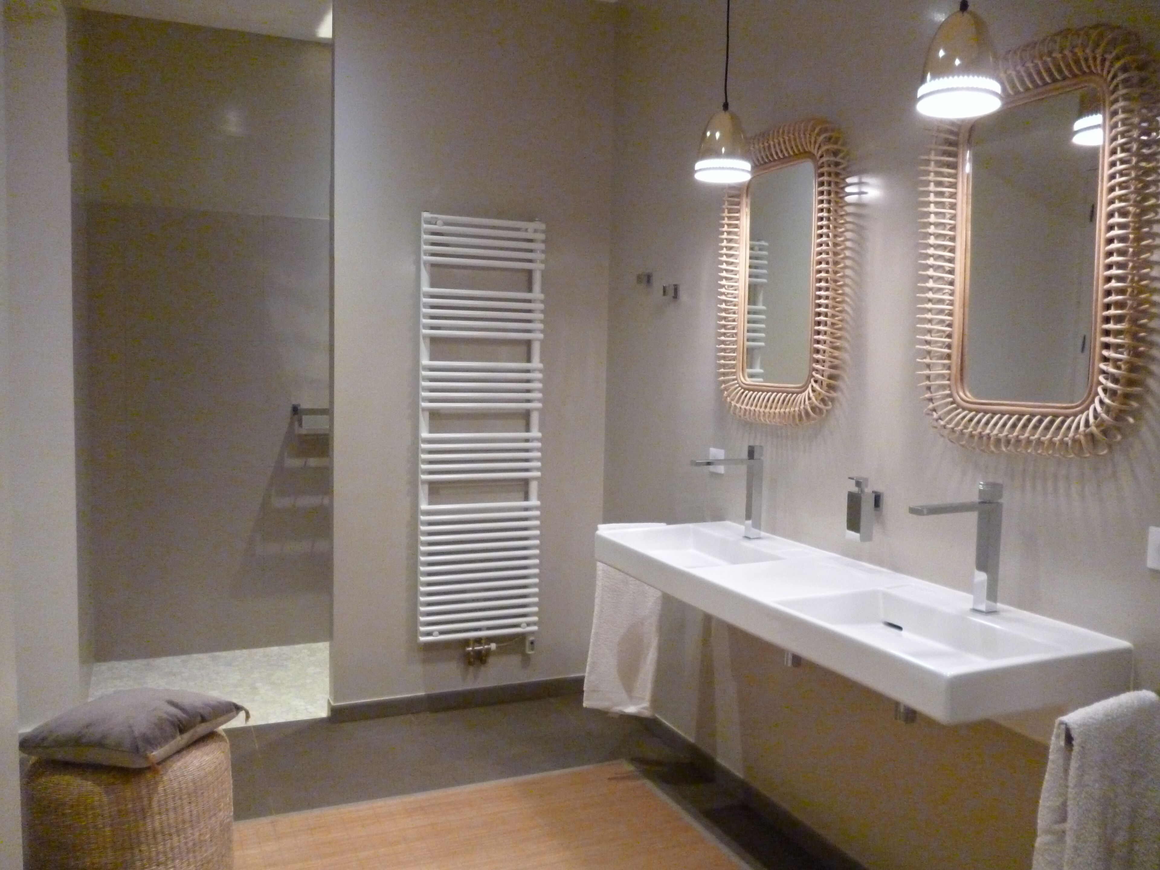 Une salle de bain moderne avec deux lavabos, un porte-serviettes et un miroir doté d’un cadre original.