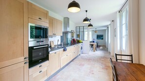 A modern kitchen with wooden cabinets, stainless steel appliances, and pendant lighting. - Chateau in magnificent park with swimming pool (Thuir)