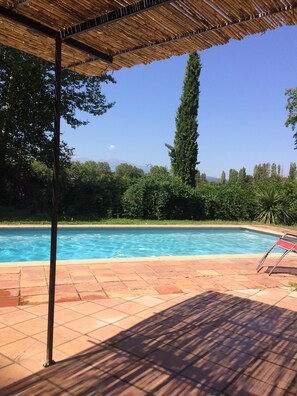 A swimming pool with a tiled deck, surrounded by greenery and a clear sky. - Chateau in magnificent park with swimming pool (Thuir)
