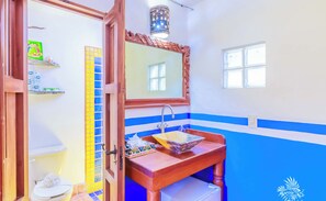 Une salle de bain avec un lavabo en bois, un miroir, des toilettes et un mur recouvert de carreaux bleus et blancs.