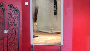 A red-walled hallway with a metal gate, a staircase, and a small indoor plant. - Jacques' workshop (Villy)