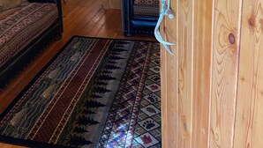 A cozy wooden cabin interior with a sofa, a patterned rug, and a chair. - Tamarack Cabin at Columbia Mountain Ranch (Columbia Falls)