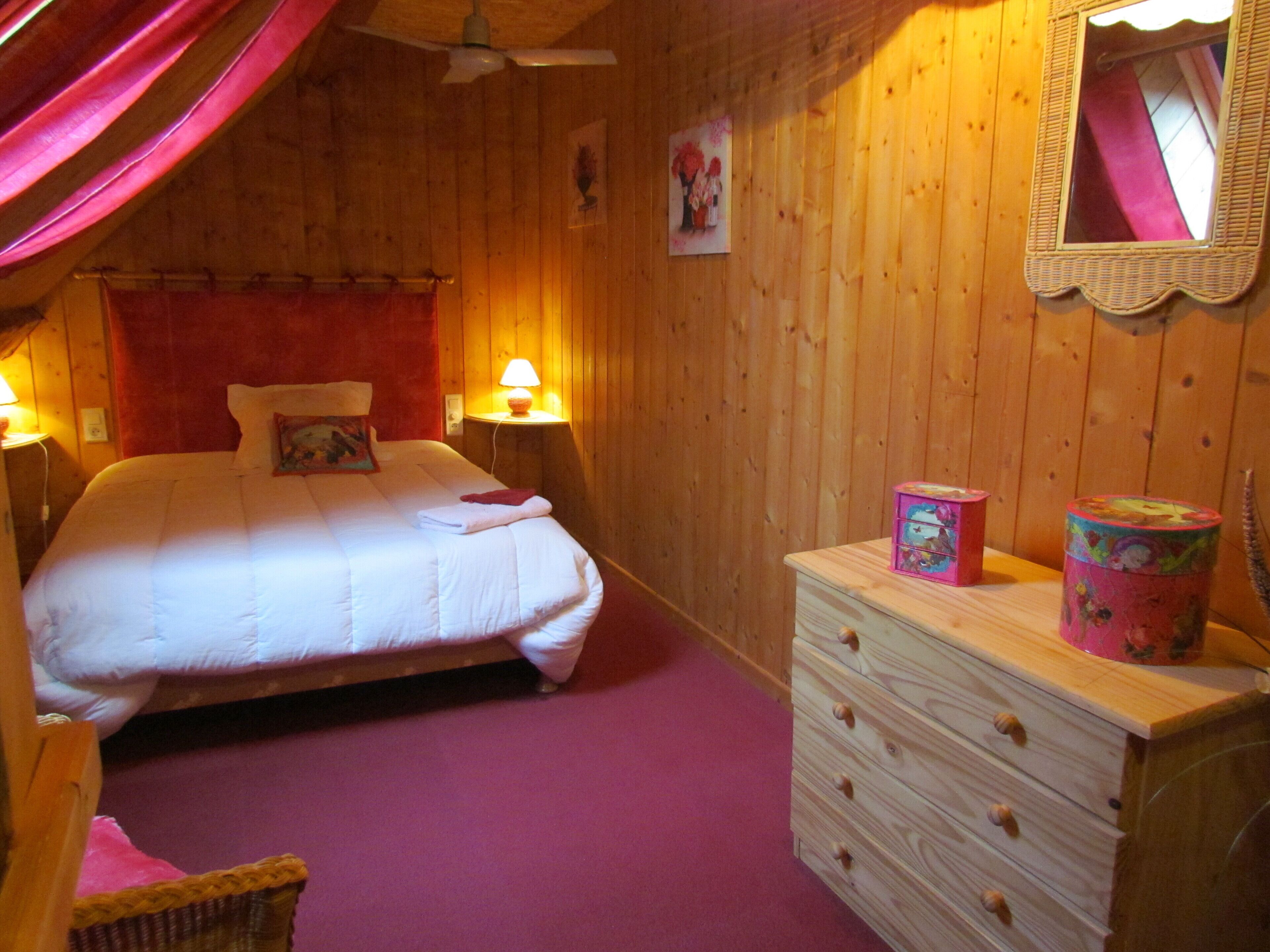 A wooden room with a bed, a dresser, and a mirror on the wall.