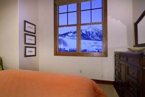 A bedroom with a large window, a bed, a dresser, and framed fish pictures on the wall.