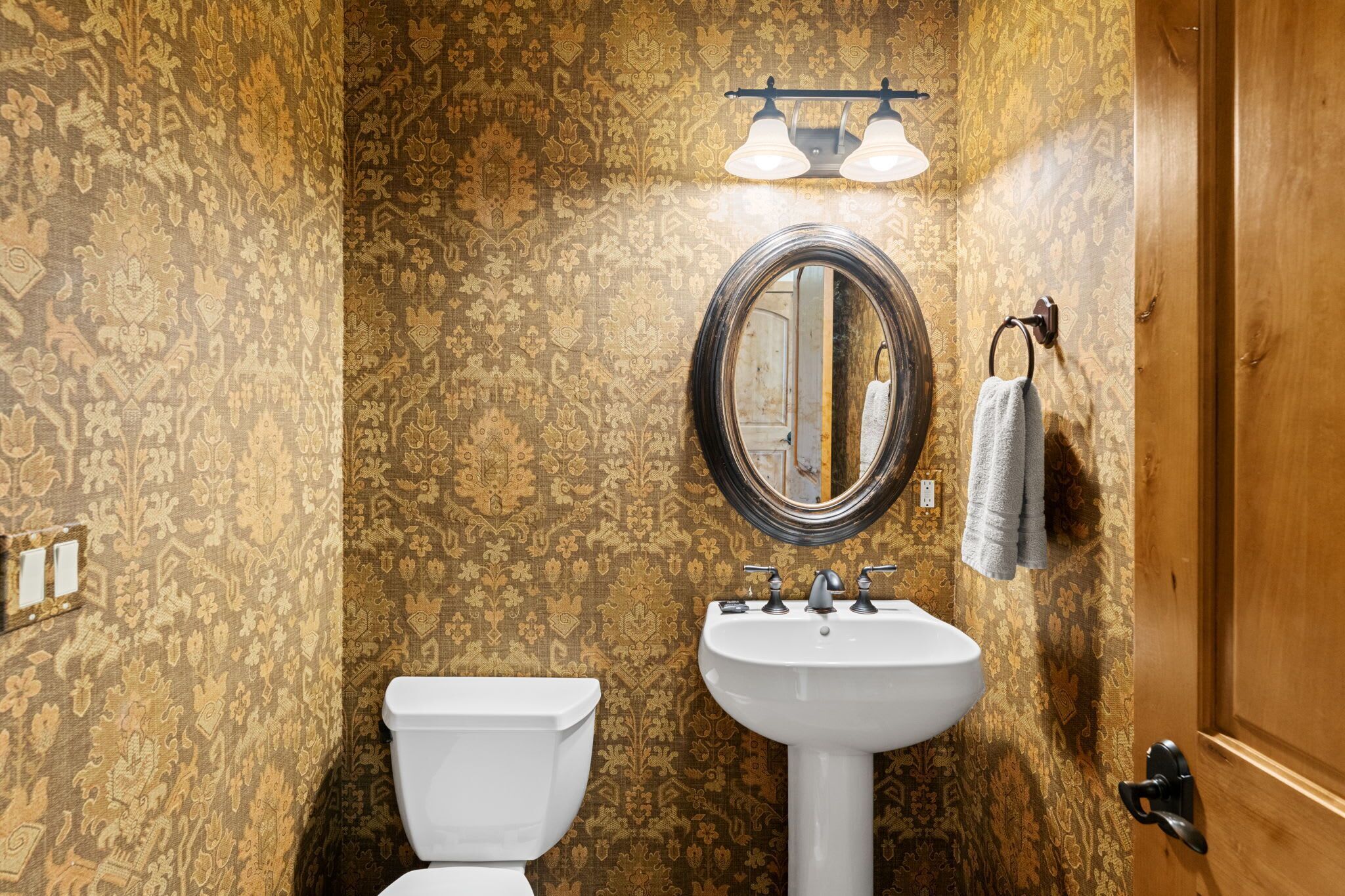 A bathroom with a toilet, sink, and mirror.