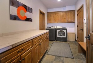 A compact kitchen with wooden cabinets, a countertop, a washing machine, and a rug on the floor.
