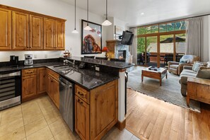 A modern kitchen with wooden cabinets, a large island, and a dining area with a view.