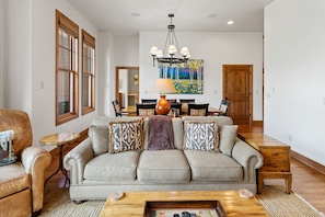 A living room with a sofa, coffee table, and a painting on the wall. - Grand Villa (Crested Butte)