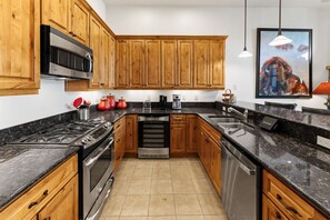 A modern kitchen with wooden cabinets, stainless steel appliances, and a tiled floor.