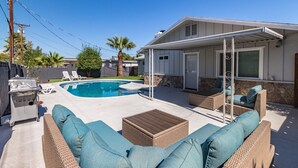 Ein Garten mit Swimmingpool, Gartenmöbeln und einer überdachten Terrasse.