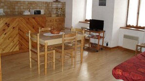 A compact living space with a dining area, kitchen, and a television. - Mountain apartment 6 people (Génos)