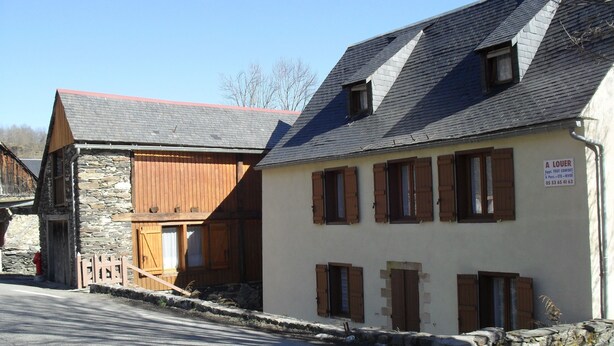 A traditional stone and wooden building with multiple windows and a sign indicating it is a bed and breakfast. - Mountain apartment 6 people (Génos)