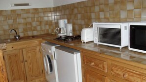 A kitchen with wooden cabinets, a washing machine, a coffee maker, and a microwave. - Mountain apartment 6 people (Génos)
