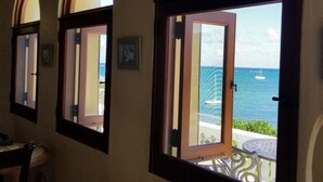 Quarto com três janelas em arco com vista para uma piscina e o mar.
