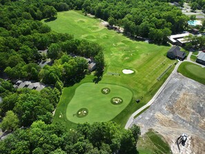 An aerial view of a golf course with multiple greens, sand bunkers, and a clubhouse.