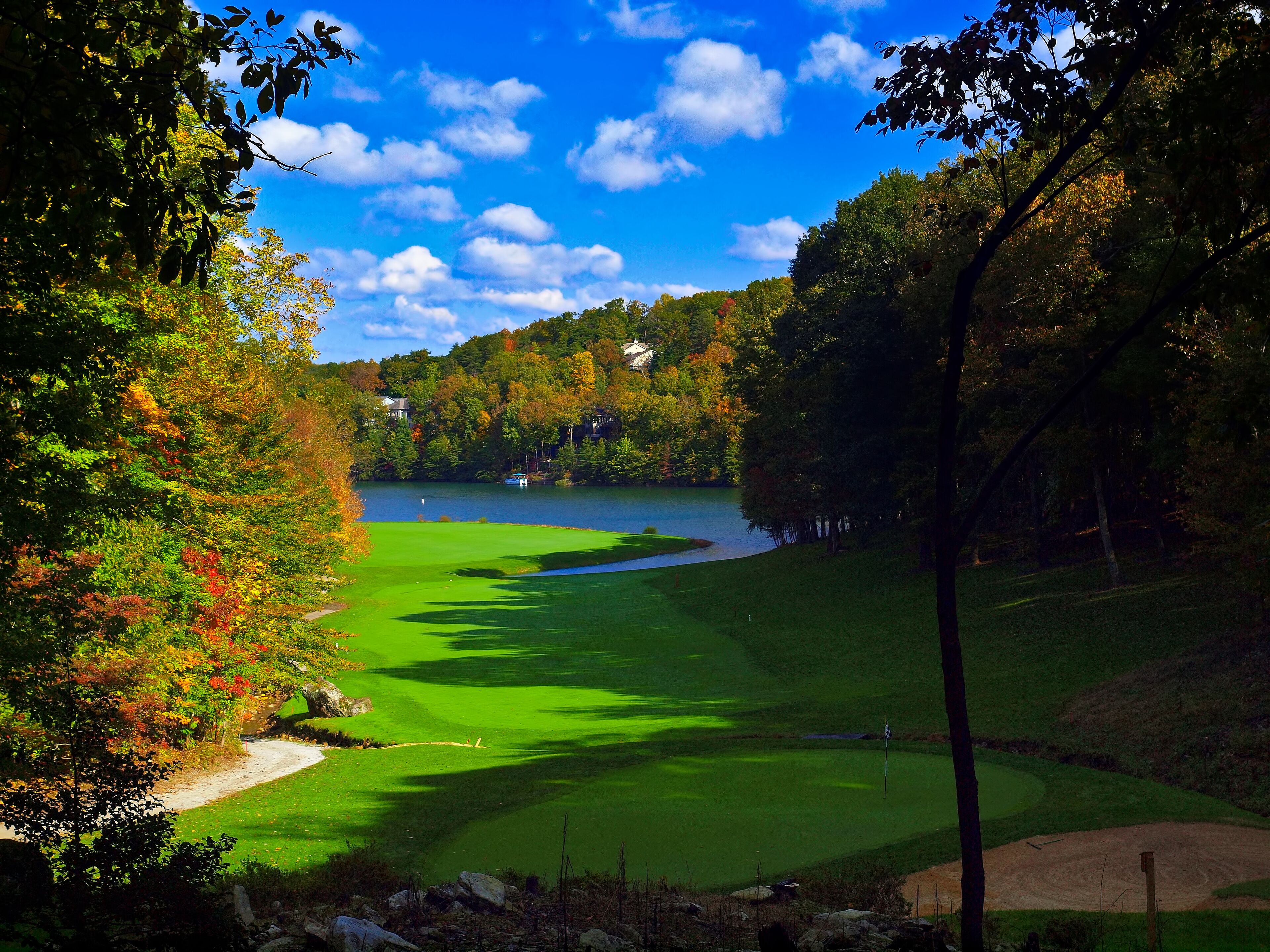 A golf course with a lake, surrounded by trees and houses.